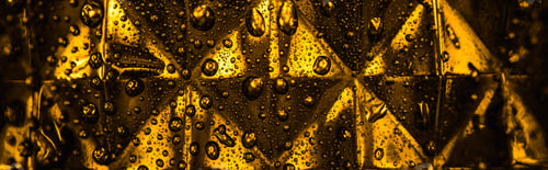 Preview: close up view of geometric faceted glass with yellow illumination in dark, panoramic shot