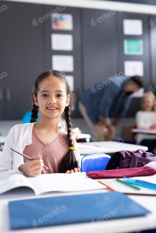 Preview: Vertical of smiling caucasian schoolgirl working in elementary school classroom, with copy space
