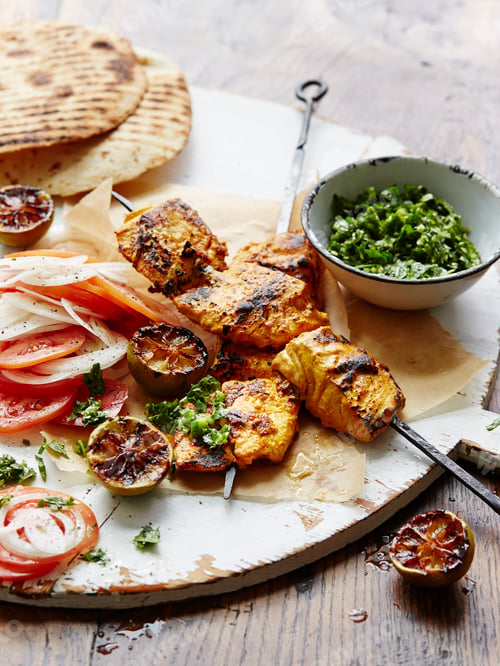 Preview: Grilled chicken and vegetables with flatbread on a wooden table.