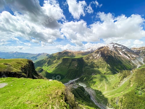 Preview: Beautiful landscape with mountains and peaks in the snow and a valley with roads and a lake