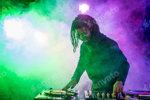 Preview: professional african american DJ in headphones with sound mixer in nightclub