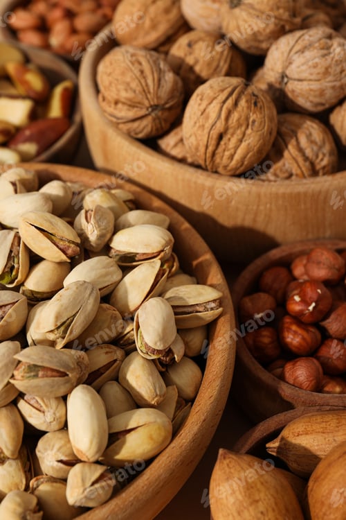 Preview: Various nuts in wooden bowls on a beige background