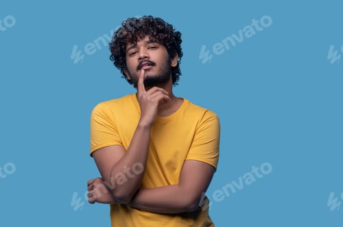 Preview: Calm relaxed guy touching his face with the forefinger