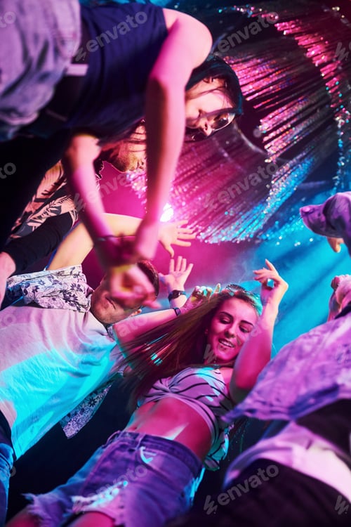 Preview: View from below of young people that having fun in night club with colorful laser lights
