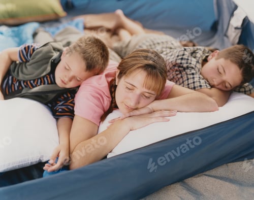 Preview: A mother and her two young sons resting in camping tent on beach