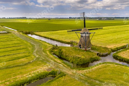 Preview: Old wooden windmill in green agricultural grassland