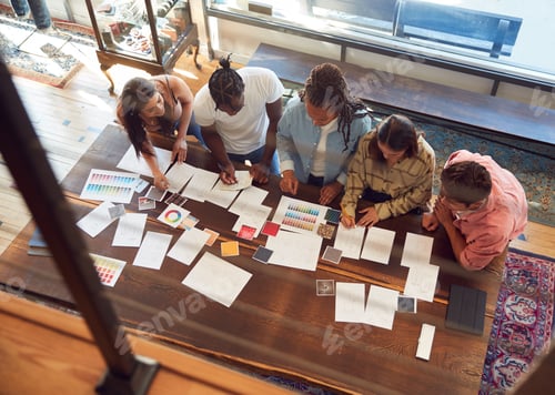 Preview: Overhead View Of Team Having Creative Design Meeting Around Wooden Table In Office