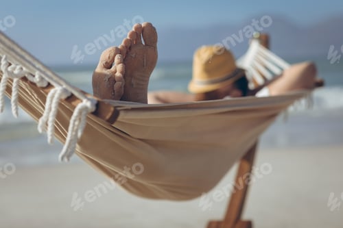 Preview: Front view of young Caucasian man relaxing on hammock at beach on a sunny day