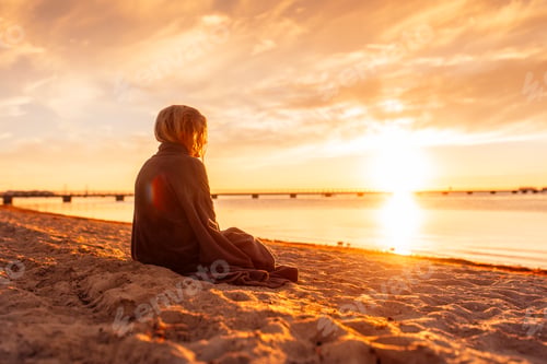 Preview: Girl (8-9) sitting on beach at sunset