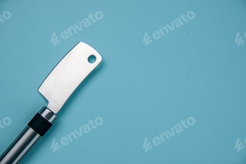 Preview: Top view of stainless meat cleaver lying on the right side on pastel blue wave background with free