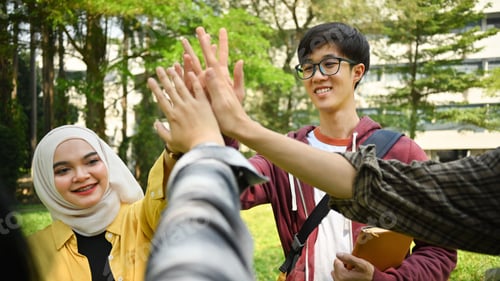 Preview: Happy university friends are giving high five, celebrating together.