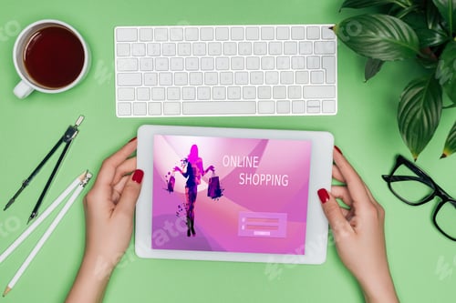 Preview: cropped image of female architect holding digital tablet with online shopping on screen at table
