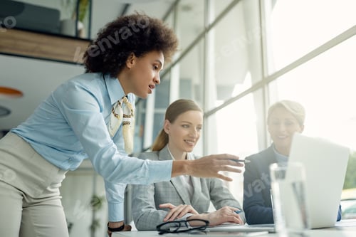 Preview: African American businesswoman working on laptop with her female colleagues in the office.