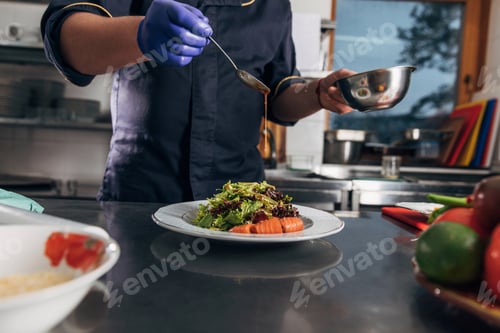 Preview: cropped shot of chef pouring sauce onto salad