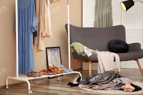 Preview: Messy dressing room with wardrobe rack and stylish armchair