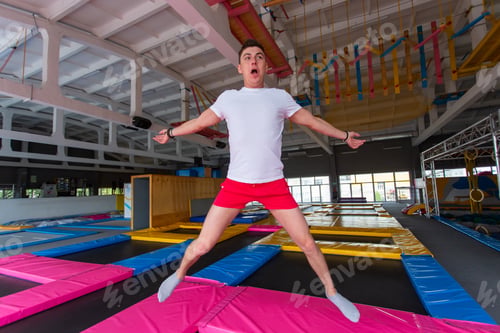 Preview: Fitness, fun, leisure and sport activity concept - Handsome happy man jumping on a trampoline