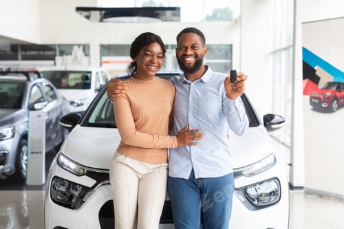 Preview: Happy Black Couple Posing With Car Keys In Hands In Dealership Center