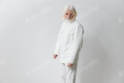 Preview: Stylish elderly man in white attire with sunglasses, posing confidently against a light gray