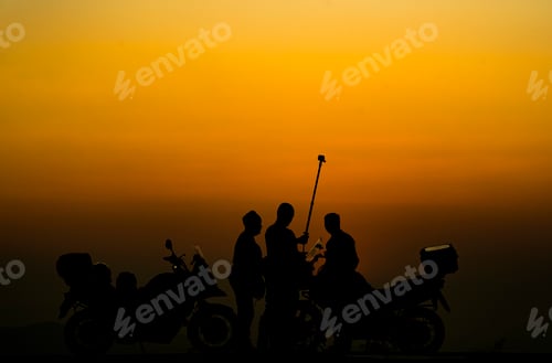 Preview: silhouette of people practicing yoga on the mountain at sunset