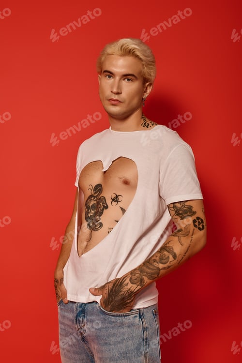 Preview: A confident young man stands against a bright red wall, showcasing his unique style and tattoos