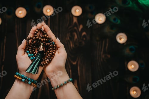 Preview: Hands Holding Prayer Beads with Candles and Feathers
