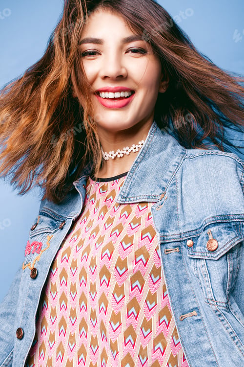 Preview: Beautiful Positive Girl In A Jeans Jacket On A Blue Background Smiling And Posing