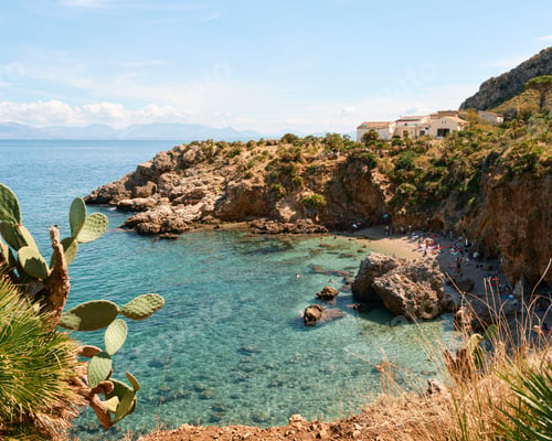Preview: A scenic view of a rocky coastline with clear turquoise water and a small beach.
