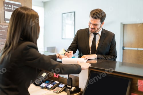 Preview: Businessman Signing Document With Clerk At Front Desk