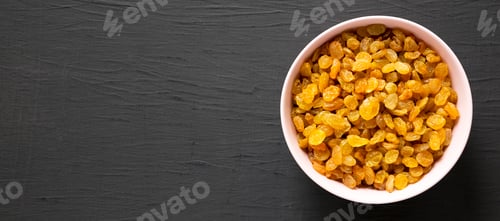 Preview: Golden Raisins in a Pink Bowl on a black surface, top view. Flat lay, overhead, from above.