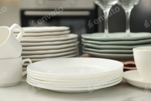 Preview: Clean plates and cups on white marble table in kitchen