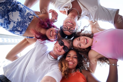 Preview: Multiethnic group of friends looking at camera cheerfully embracing each other.