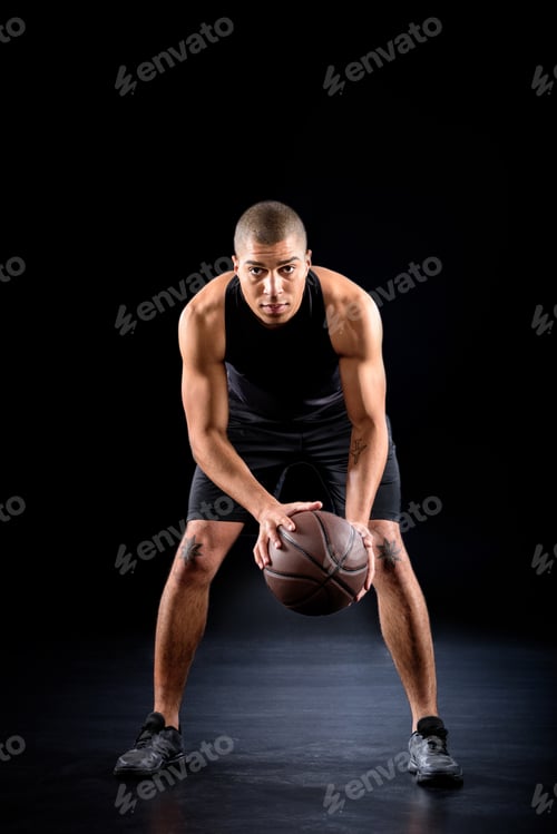 Preview: concentrated african american basketball player with ball on black