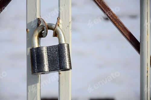 Preview: A large gray padlock hangs on a metal gate