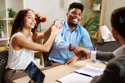 Preview: Happy couple shaking hands with financial advisor in office after signing contract