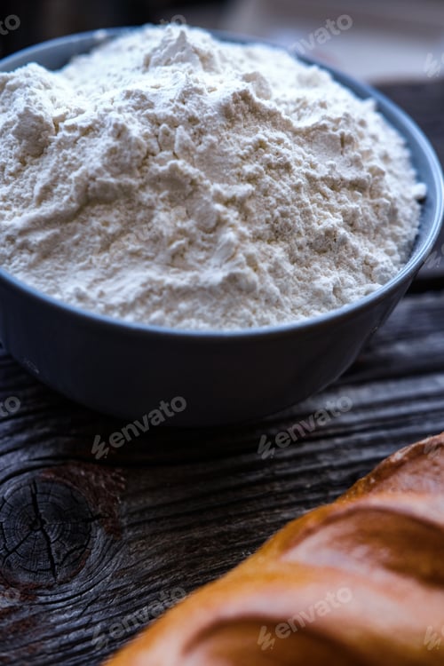 Preview: Closeup photo of bowl of white flour and bread on black wooden table