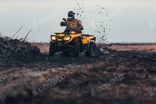 Person Riding Yellow ATV Through the Mud Outdoors