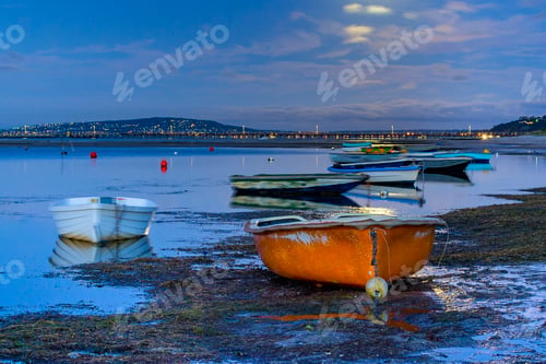 Preview: Little orange rowboat on the beach under a full moon