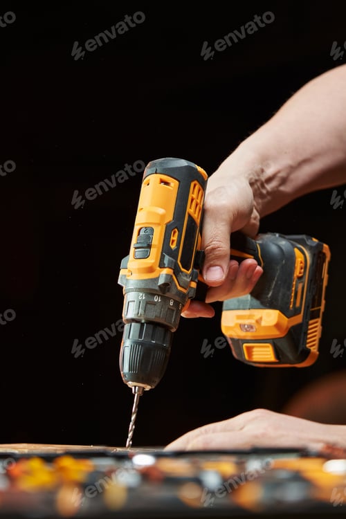 Preview: side view of a drill and an electric drill-driver with a replaceable battery held by a worker's hand