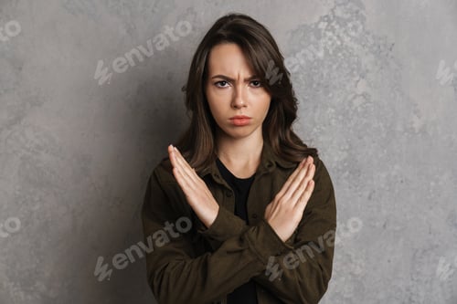 Preview: Displeased beautiful girl looking and showing stop gesture at camera