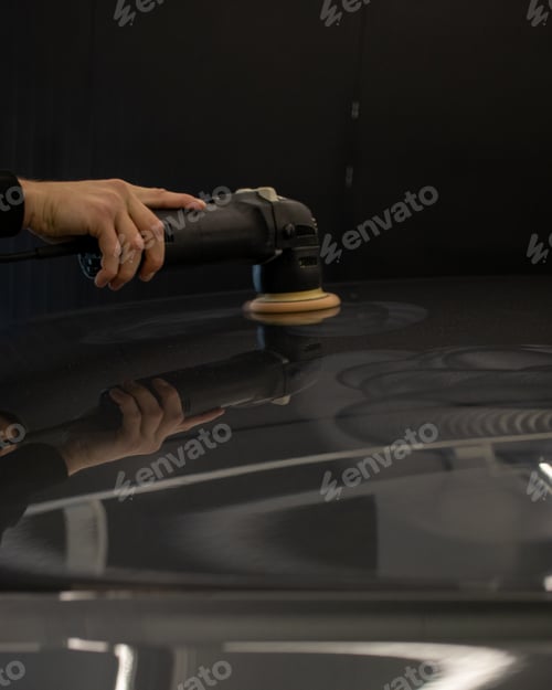 Preview: Person polishing the hood of a modern black car under the lights