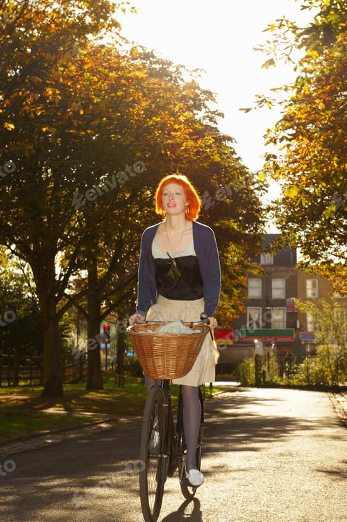 Preview: Young redhead woman cycling in park