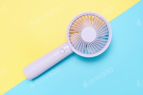 Preview: Small portable mini fans on blue and yellow background close-up.