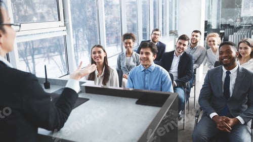 Preview: Young business team listening to speaker at meeting