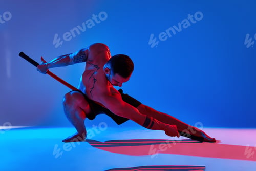 Preview: athlete men with stick training karate using sports tool in studio on colorfull lights background