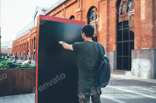 Preview: Young man pointing on empty banner in street