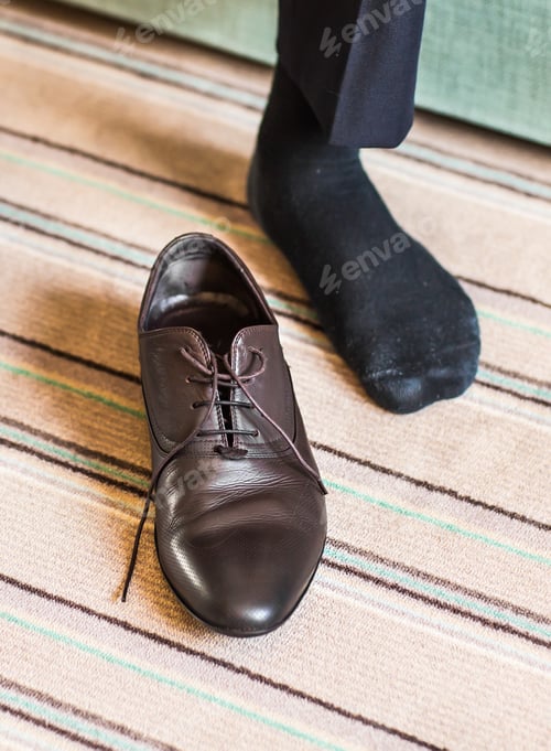 Preview: Close-up young man tying elegant shoes indoors