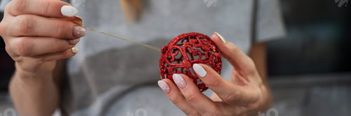 Preview: Attaching a golden string to red christmas bauble