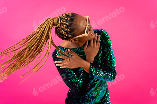 Preview: African young woman with party braids on a pink background, having fun dancing moving her hair