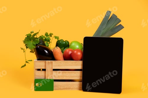 Preview: Digital Tablet Standing Near Vegetables In Box On Yellow Background
