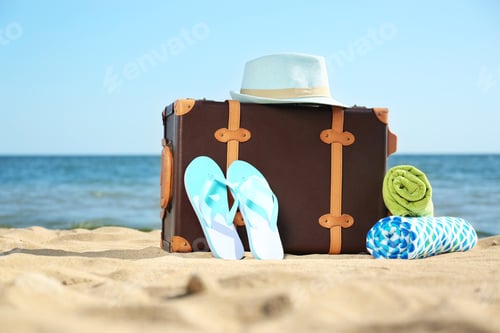 Preview: Suitcase and beach accessories on sand near sea. Space for text